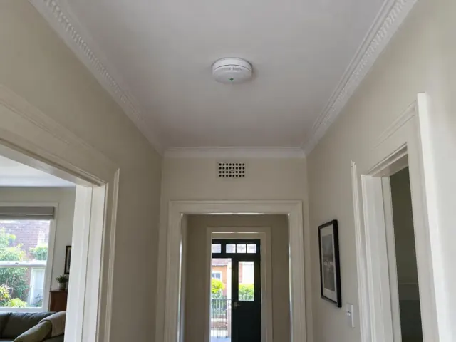 Ceiling smoke alarm in a hallway with ornate cornices and doorways in Kirribilli